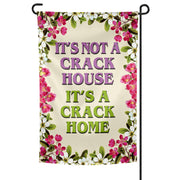 A rectangular garden flag with a floral border and a central text that reads 'IT'S NOT A CRACK HOUSE IT'S A CRACK HOME' in capital letters.