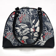 A black handbag with a multicolored mushroom pattern on the side, featuring foam padding and premium zippers.